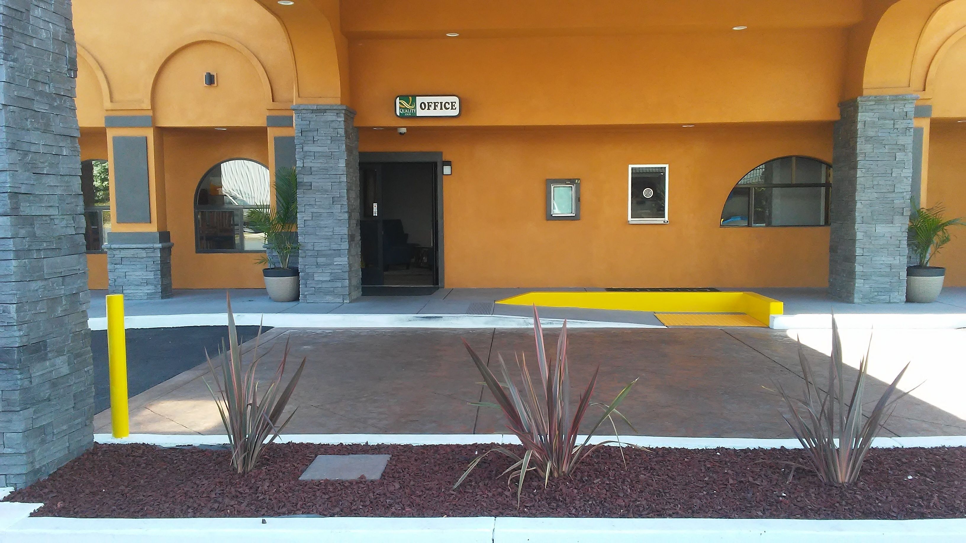 An office building with a yellow facade, stone pillars, and a sign indicating an office space.