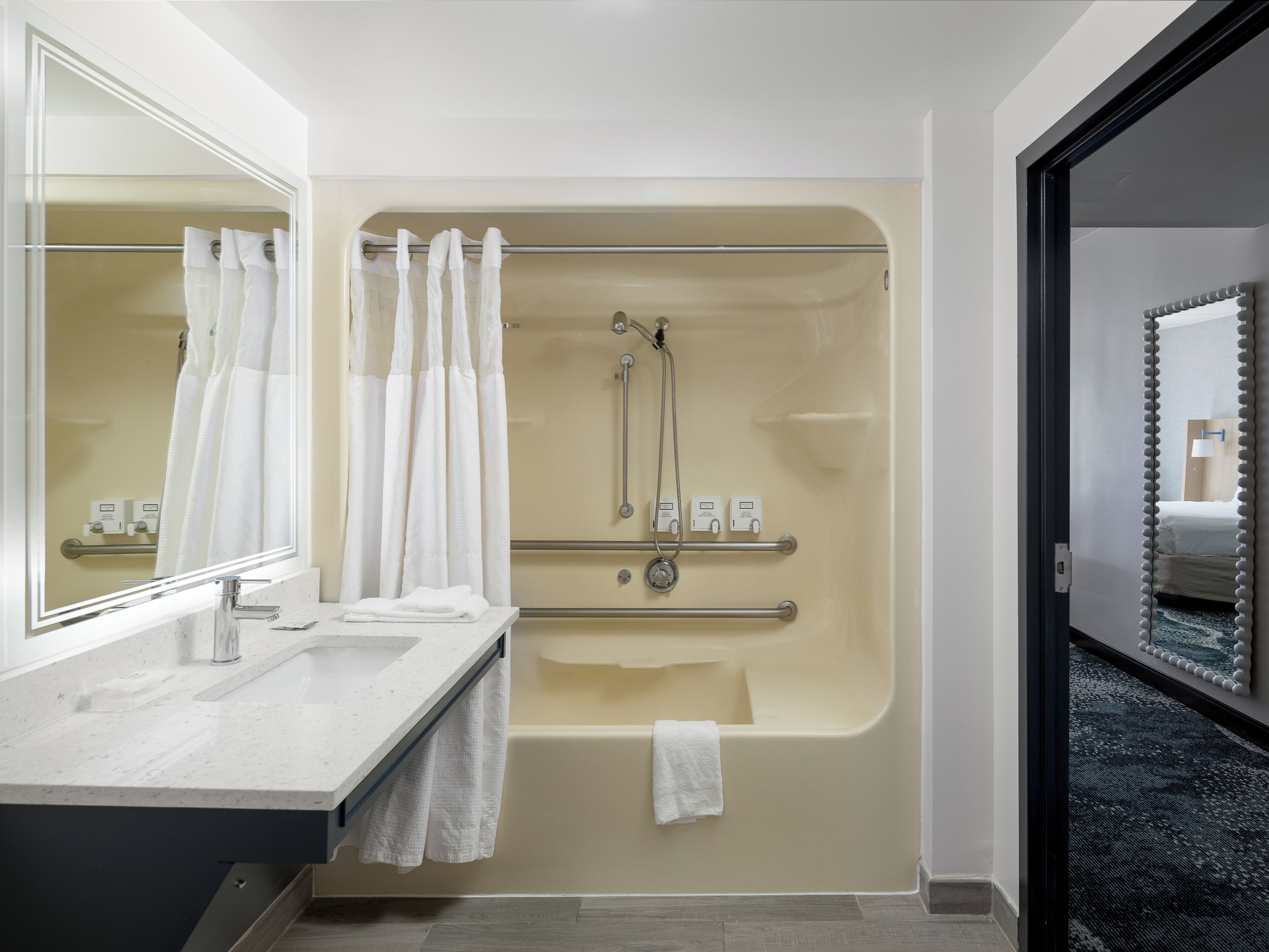 A modern bathroom with a bathtub, shower, and a vanity with a mirror.