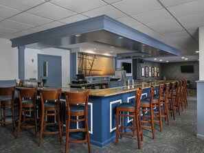 A bar area with a long counter, multiple bar stools, and a large window with a view.
