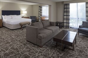 Ein Hotelzimmer mit einem Bett, einem grauen Sofa, einem kleinen Tisch und einem Sessel.