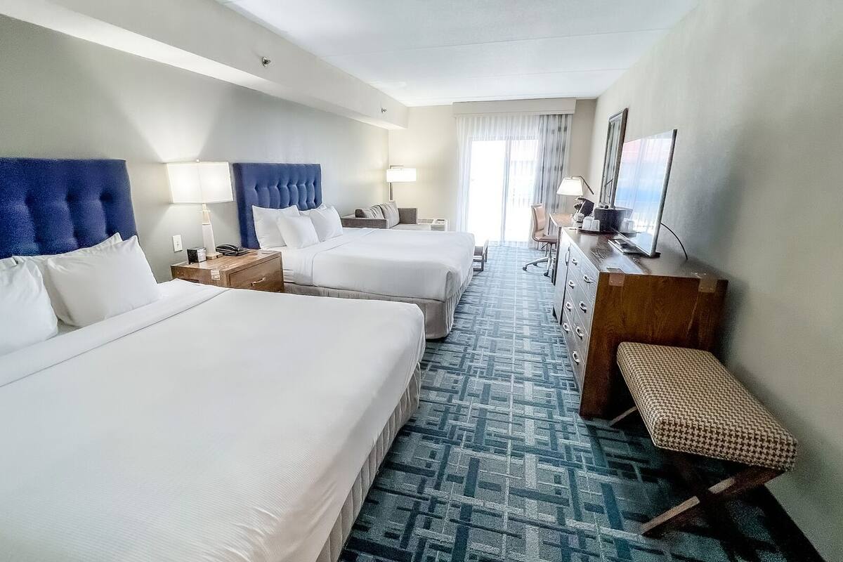 Une chambre d’hôtel avec deux lits, un bureau, une chaise et une commode.
