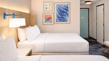 Een hotelkamer met twee bedden, een nachtkastje, een wandlamp en kunstwerken.