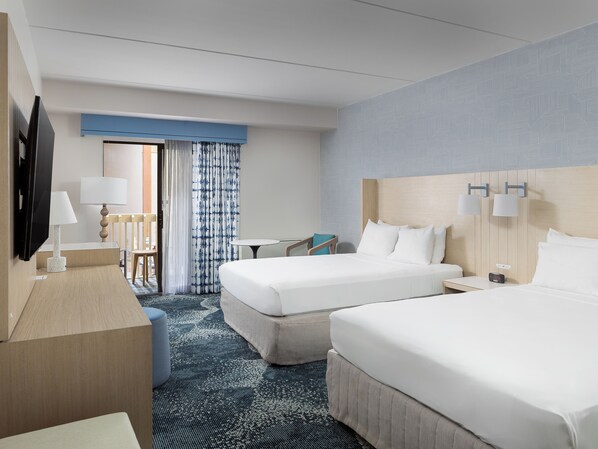 Habitación de hotel con dos camas, un escritorio, una silla, un televisor y una ventana con cortinas.