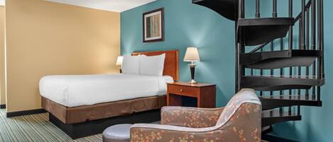 Une chambre d’hôtel avec un lit, une chaise, une table de chevet, une lampe et un escalier en colimaçon.