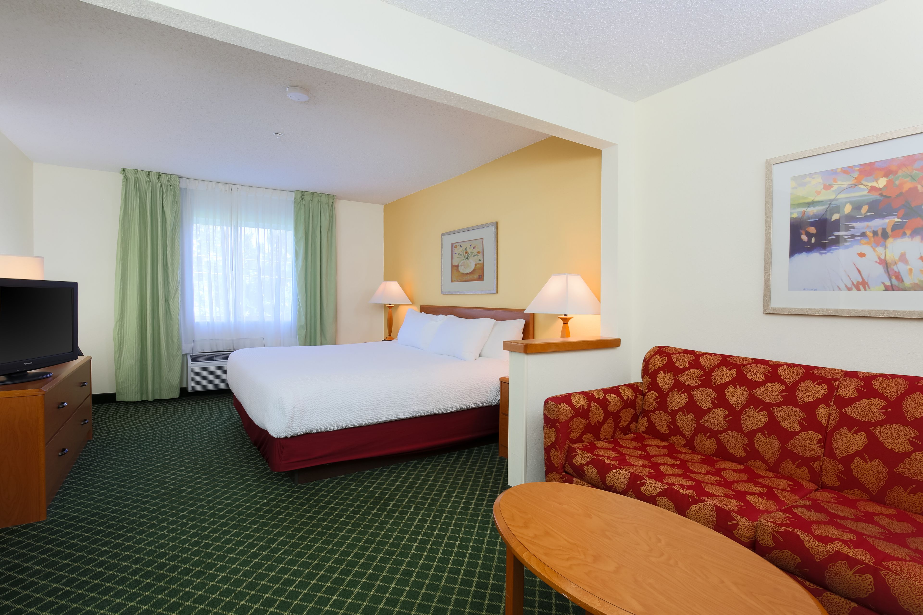 A hotel room with a bed, a sofa, a TV, and a table.