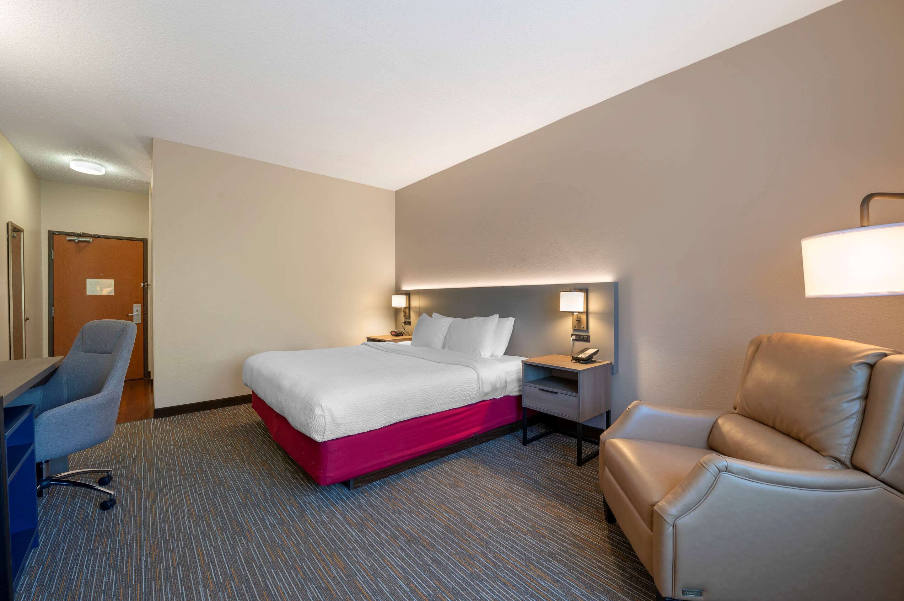 Una habitación de hotel con una cama, un escritorio, una silla y un sofá.