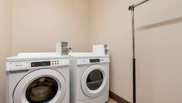 Un espace buanderie équipé de deux lave-linge à chargement frontal de la marque Whirlpool et d’un grand étendoir noir.