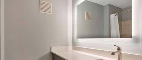 A bathroom with a toilet, a sink, a mirror, and a shower curtain.