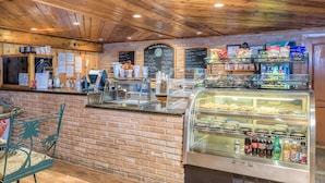 Eine Bäckerei mit Backsteinwand, Holzbalkendecke und einer Vitrine voller Backwaren.