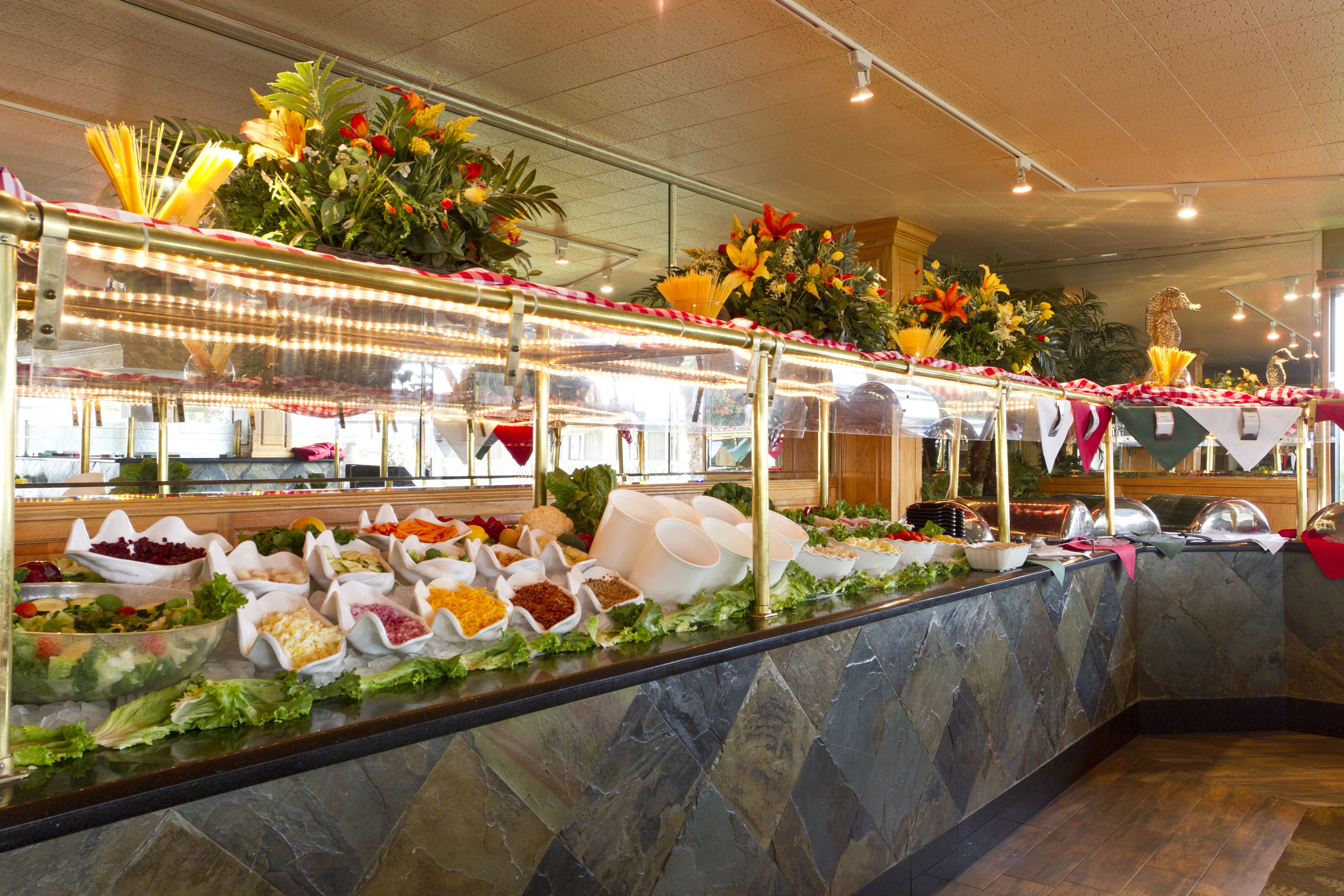 A buffet with various food items and decorative flowers.