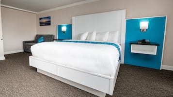 Habitación de hotel con una cama grande, un escritorio y una silla. Se observa un cuadro en la pared y una pared de acento azul.