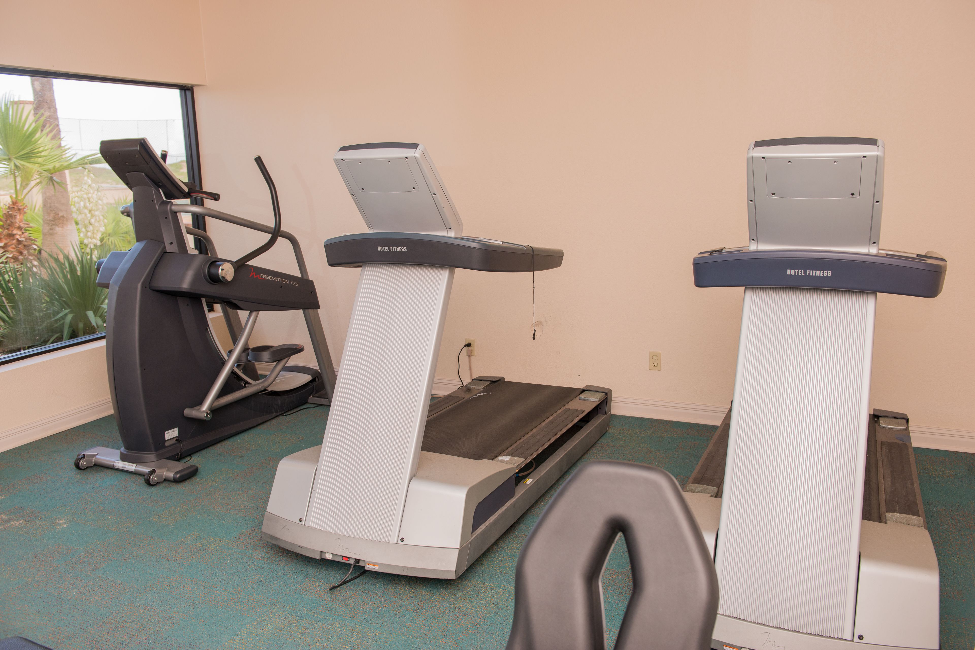 Un gimnasio con cintas de correr y una bicicleta estática.