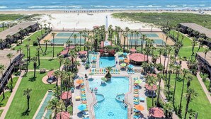 Un resort con piscina central, varias canchas de tenis y vistas a la playa.