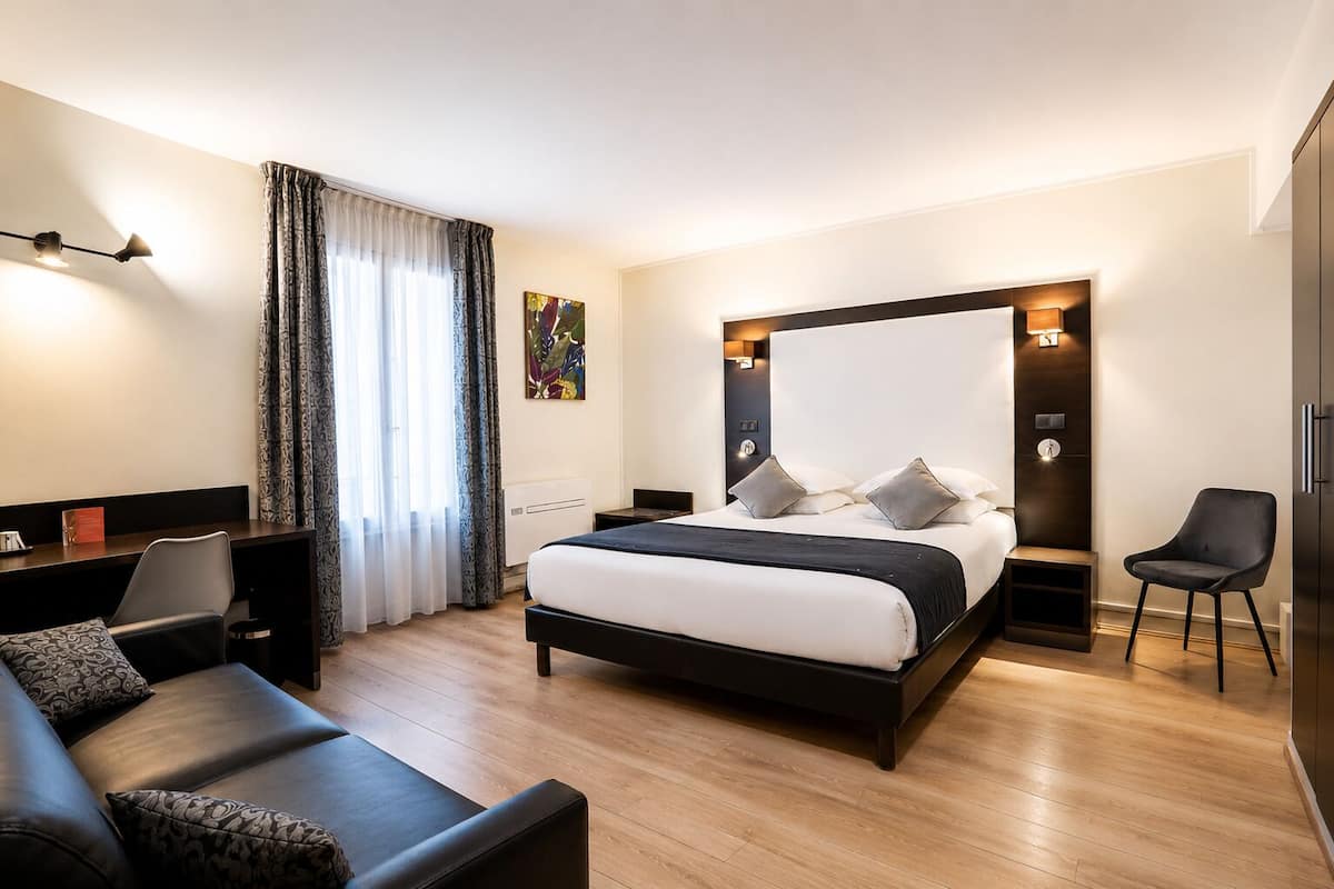 Une chambre d’hôtel moderne équipée d’un grand lit, d’un bureau, d’une chaise et d’une armoire.