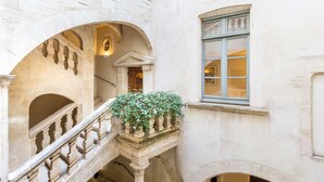 A stone building with a balcony, a window, and an archway.