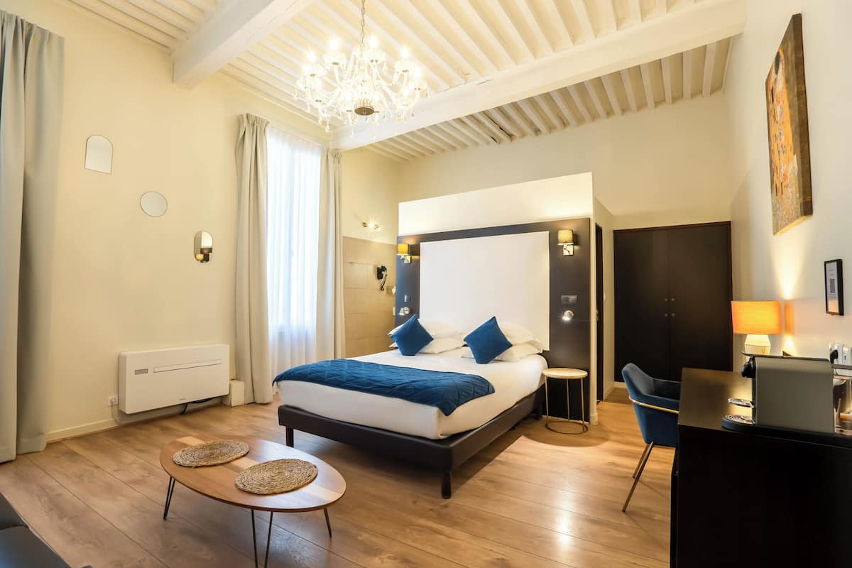 Une chambre moderne avec un grand lit, des tables de chevet, un bureau et un lustre.