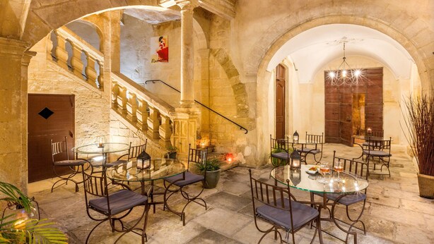 An indoor courtyard with stone walls, a glass table, and chairs.