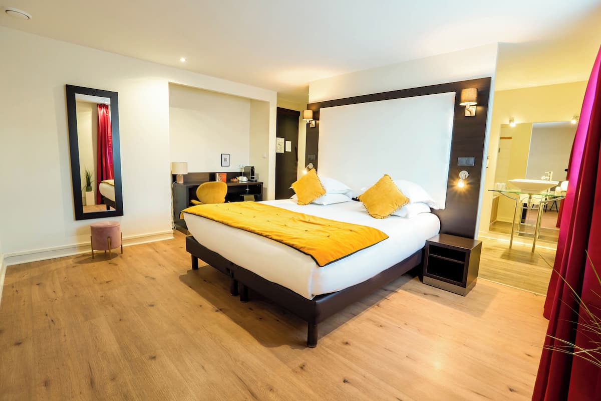 Une chambre d’hôtel moderne avec un grand lit, des tables de chevet, un bureau et un miroir.