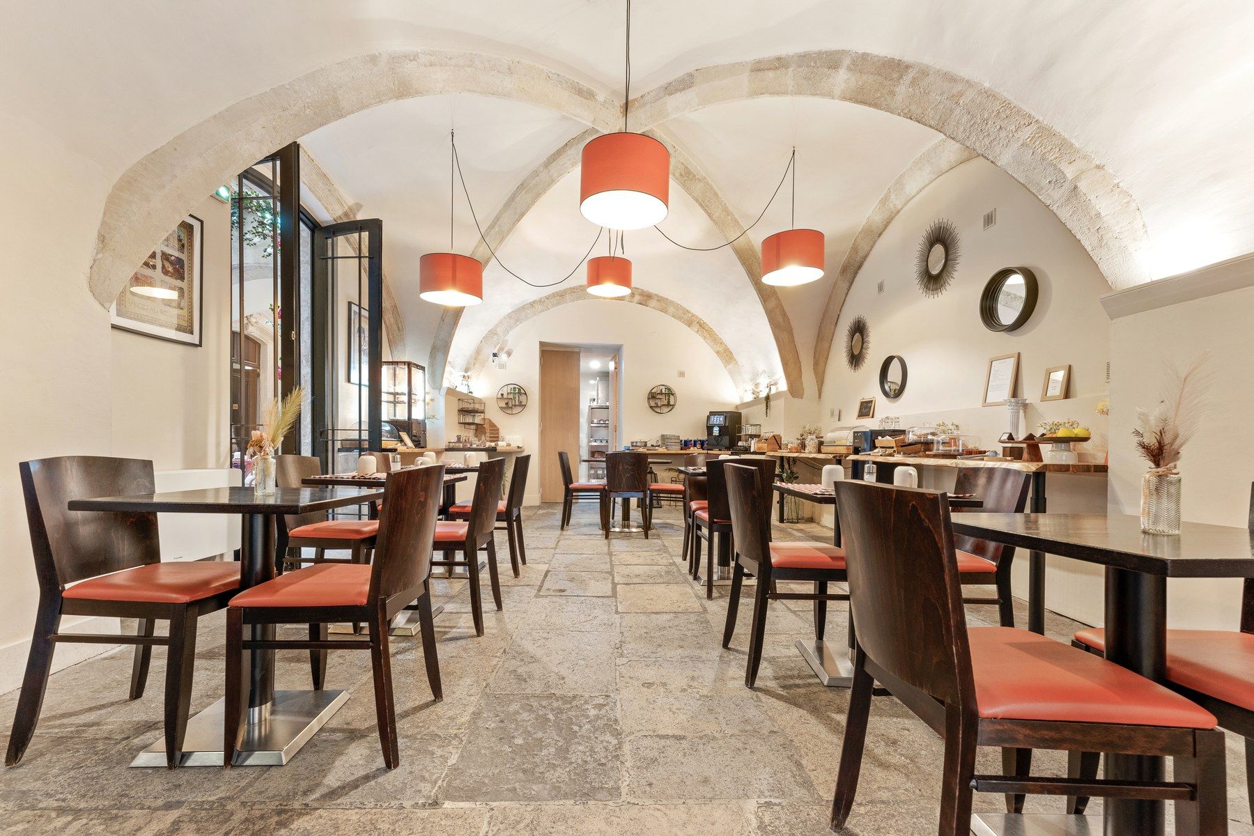 A dining area with high arched ceilings, multiple tables, and chairs with red cushions.