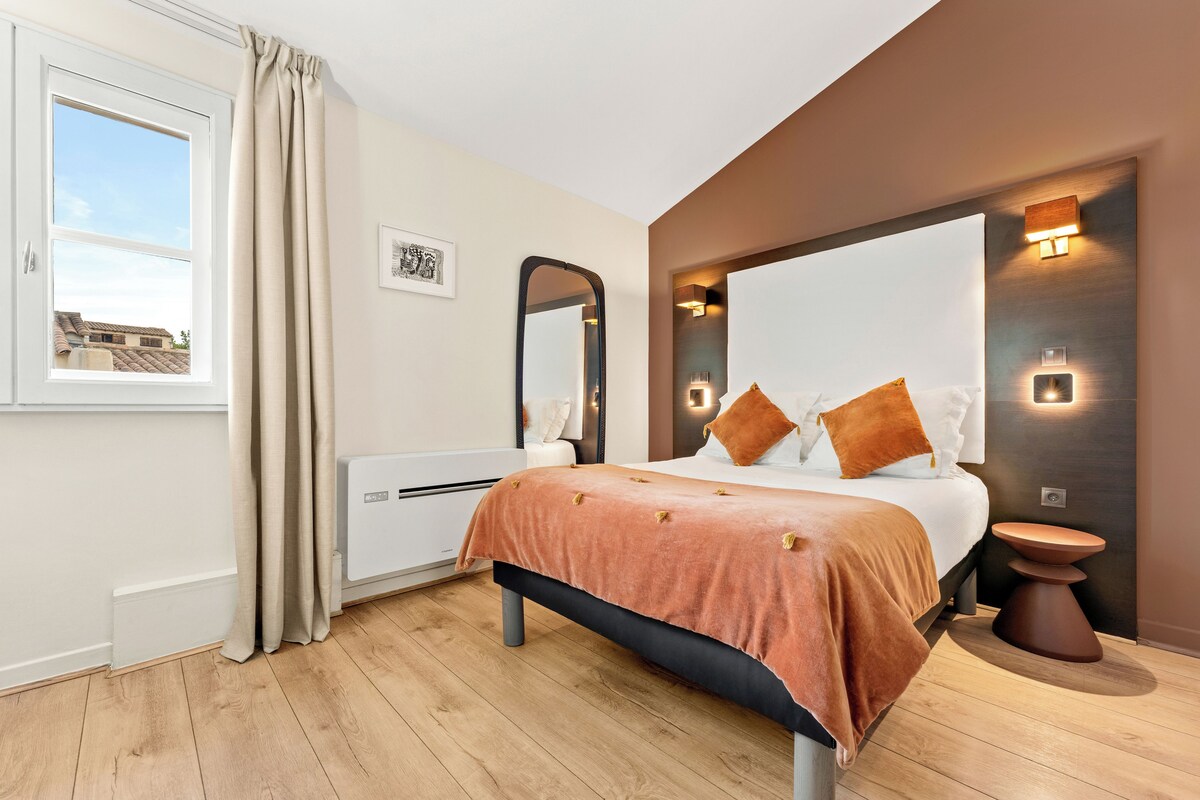 Un dormitorio moderno con cama, mesita de noche, espejo e iluminación integrada.