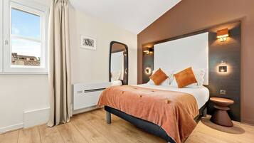 A modern bedroom with a bed, bedside table, mirror, and built-in lighting.