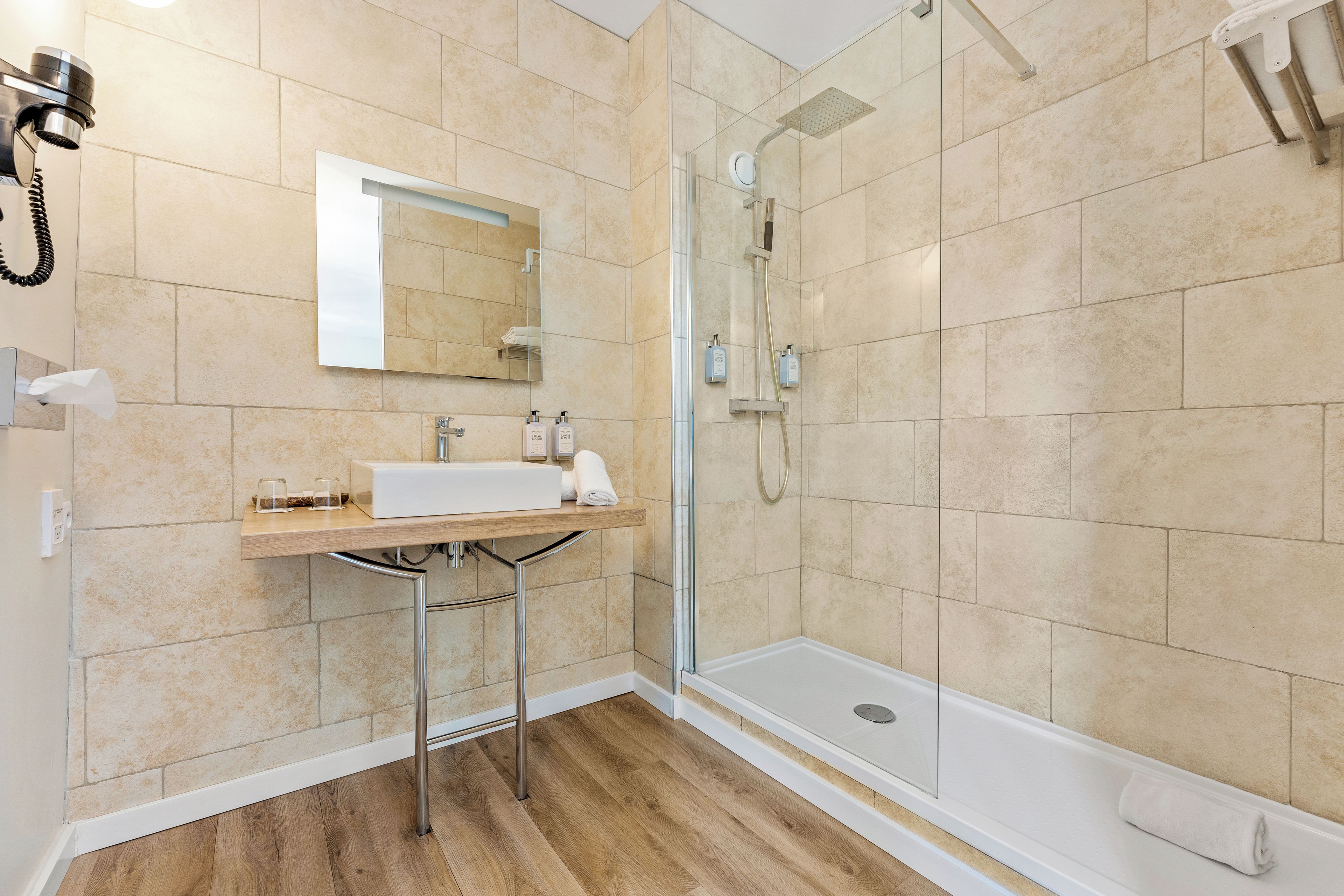 Un baño moderno con cabina de ducha de vidrio, un lavamanos blanco y un espejo encima.