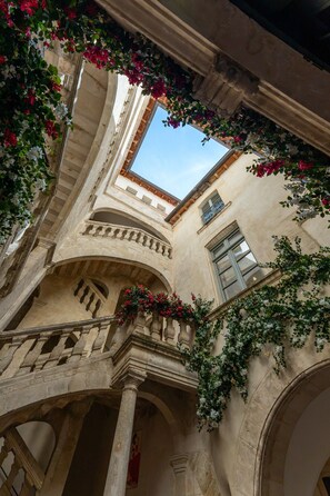 An interior courtyard with arches, columns, and a view of the sky through a skylight.