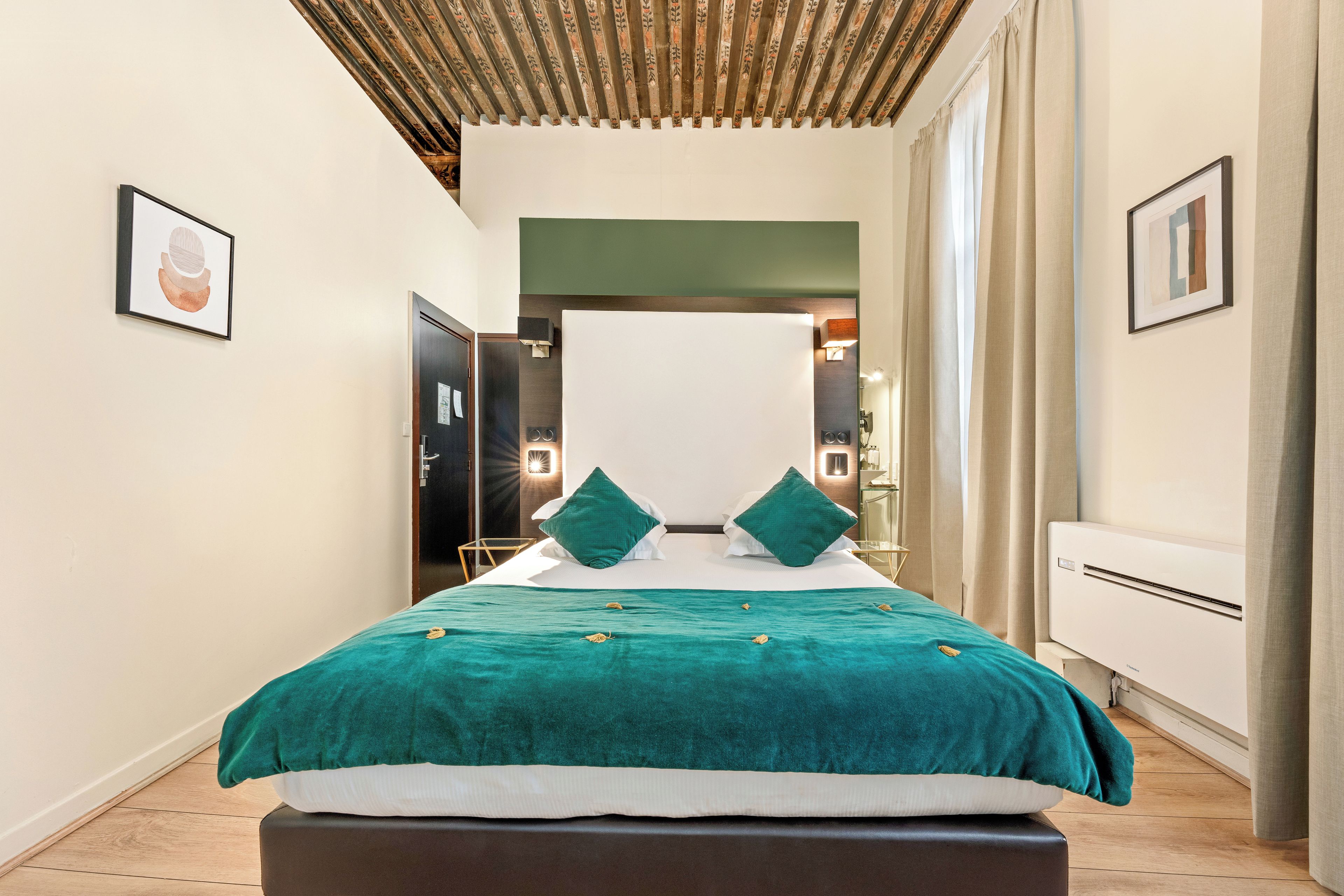 Una habitación de hotel con una cama grande, una mesita de noche, un armario y un espejo.