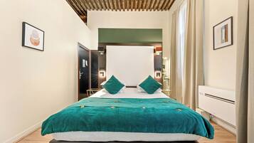 Una habitación de hotel con una cama grande, una mesita de noche, un armario y un espejo.