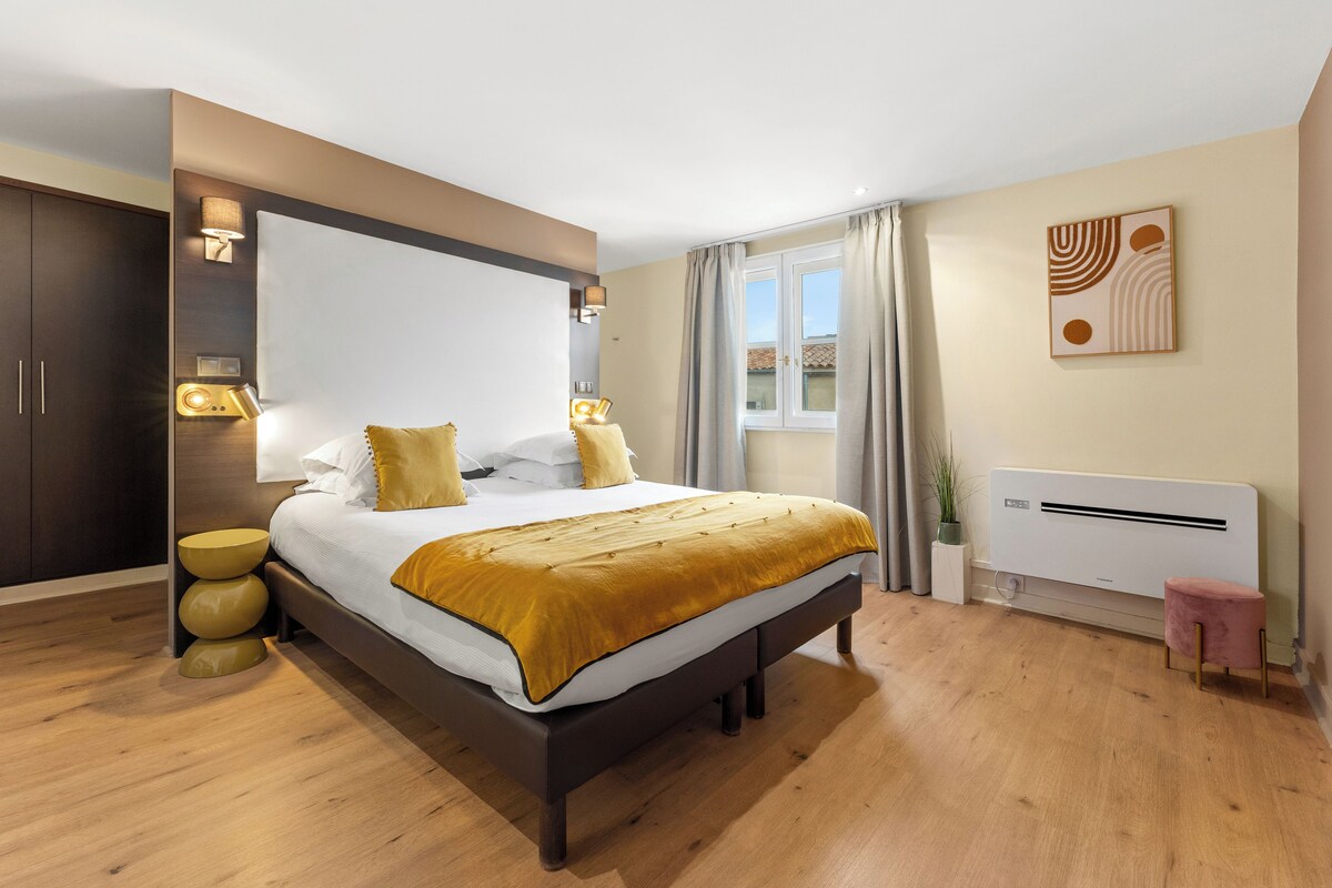 Un dormitorio moderno con una cama grande, lámparas de noche, un radiador y una ventana con cortinas.