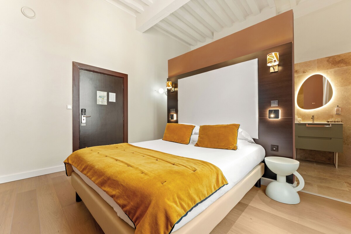 Habitación de hotel con cama, baño y techo de madera.