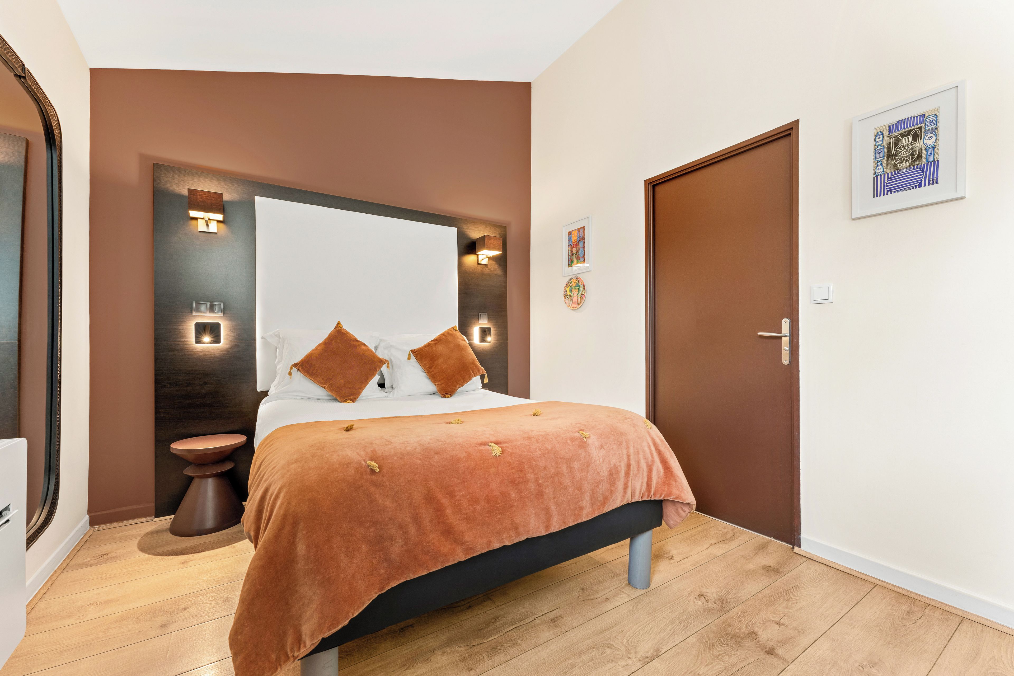 Un dormitorio con cama, mesitas de noche, un espejo y una puerta.
