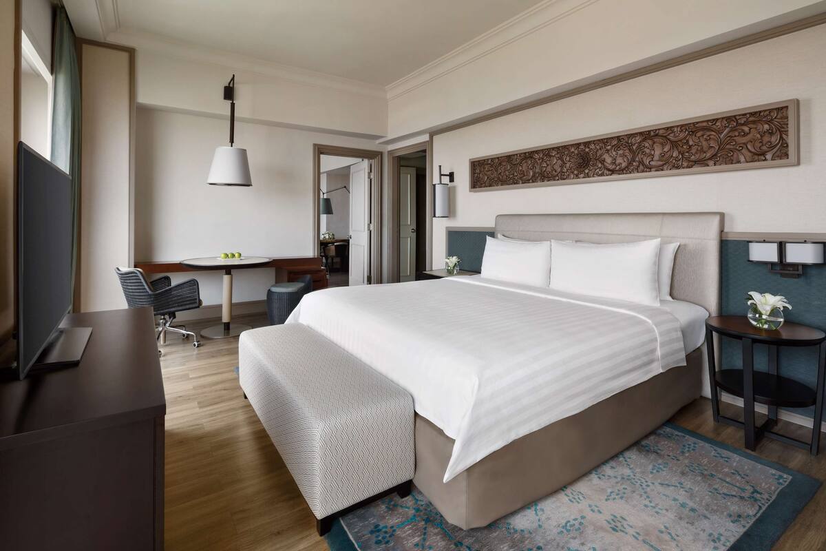Een moderne hotelkamer met een groot bed, een bureau, een stoel, een televisie en een decoratief wandobject.