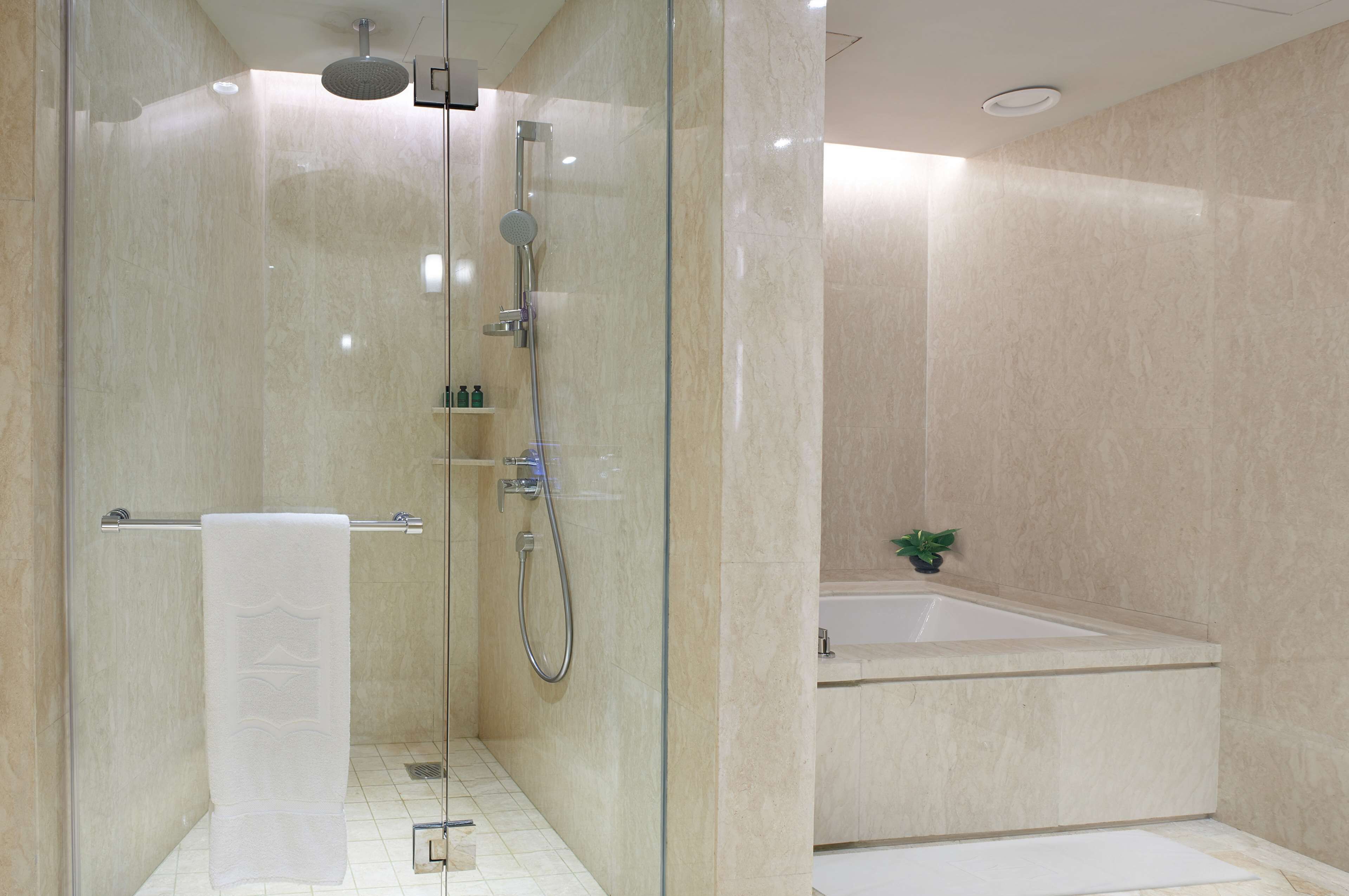 Une salle de bain moderne avec une douche à parois de verre, une baignoire et une serviette blanche posée sur un porte-serviettes.