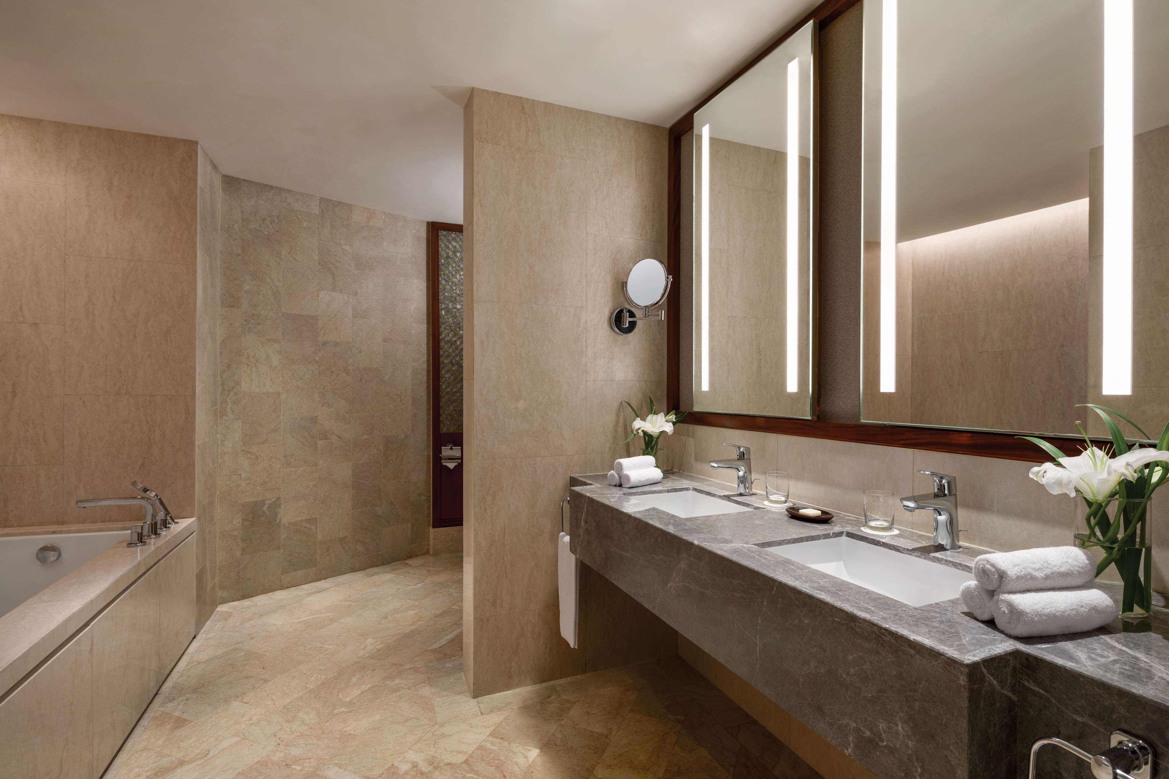 A modern bathroom with a dual sink vanity, a large mirror, and a bathtub.