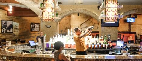 A bar area with a stone arch, bar counter, and seating.