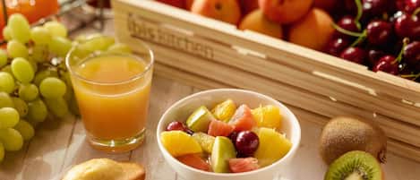 Desayuno con frutas, un vaso de zumo de naranja y un libro titulado 'The Kitchen'.