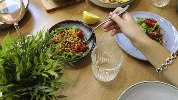 A dining table with various dishes, a glass of wine, and a potted plant.