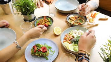 Una mesa de comedor con diversos platos y bebidas, rodeada de gente.