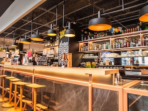 Un espace bar comprenant un comptoir, des tabourets et une variété de bouteilles et de verres.