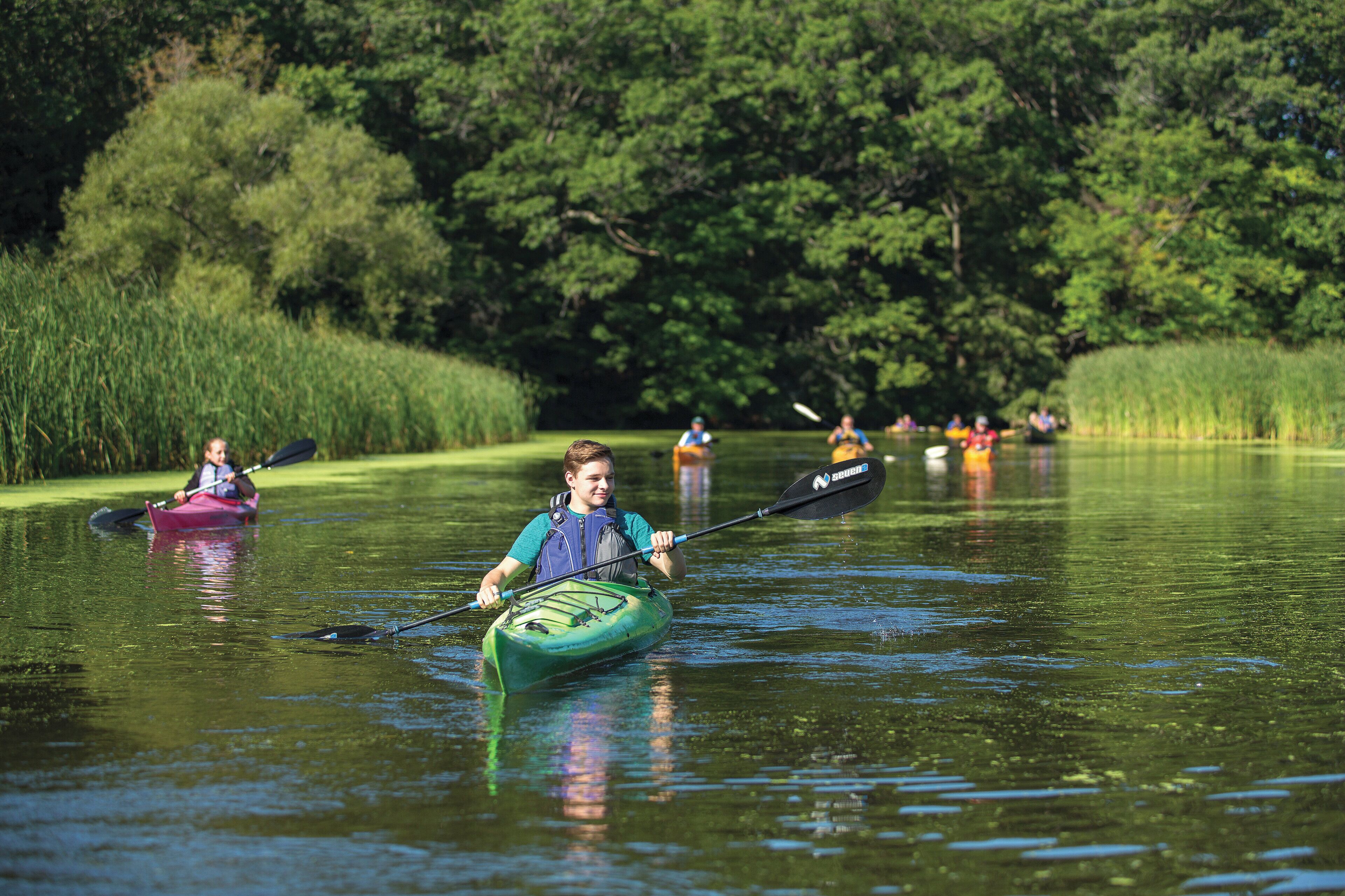 Un llac tranquil amb kayaks i una persona remant.