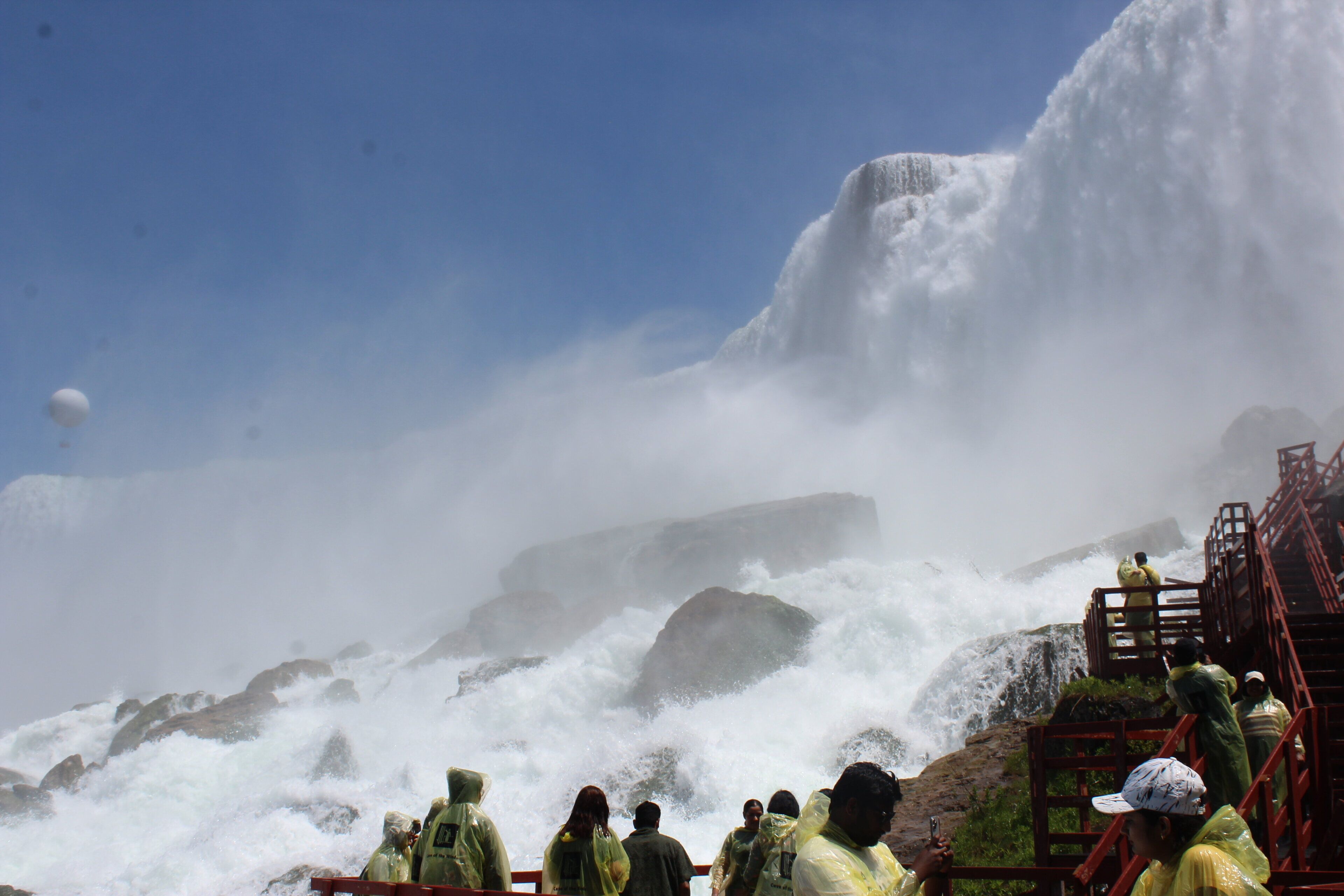 A group of people observing a waterfall with a rocky backdrop.