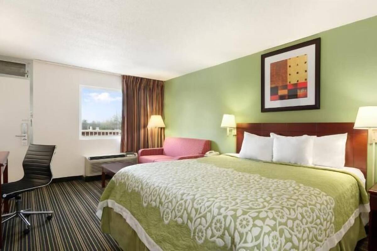 Una habitación de hotel con cama, escritorio, silla y ventana.