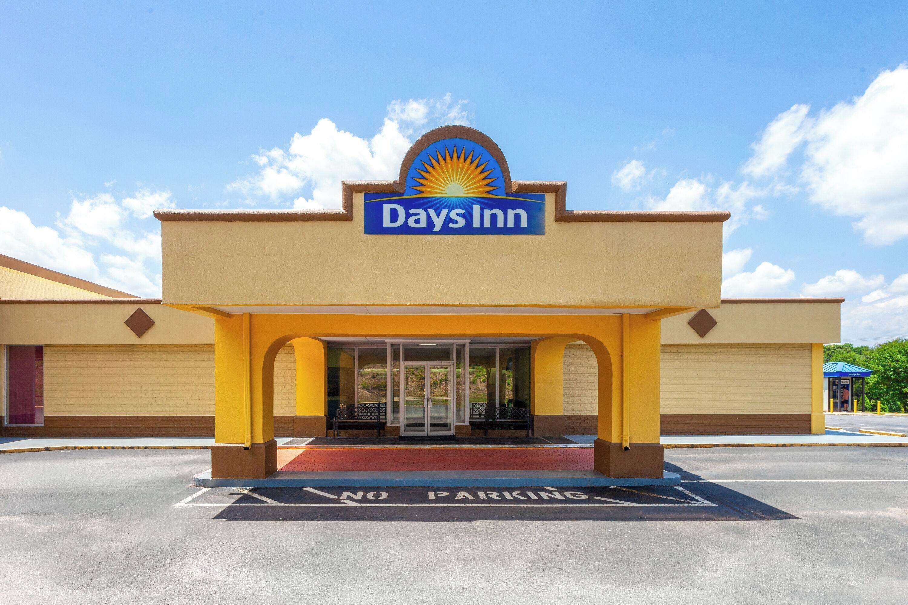 A Days Inn with a clear entrance, a 'No Parking' sign in the parking lot, and a blue sky with clouds.
