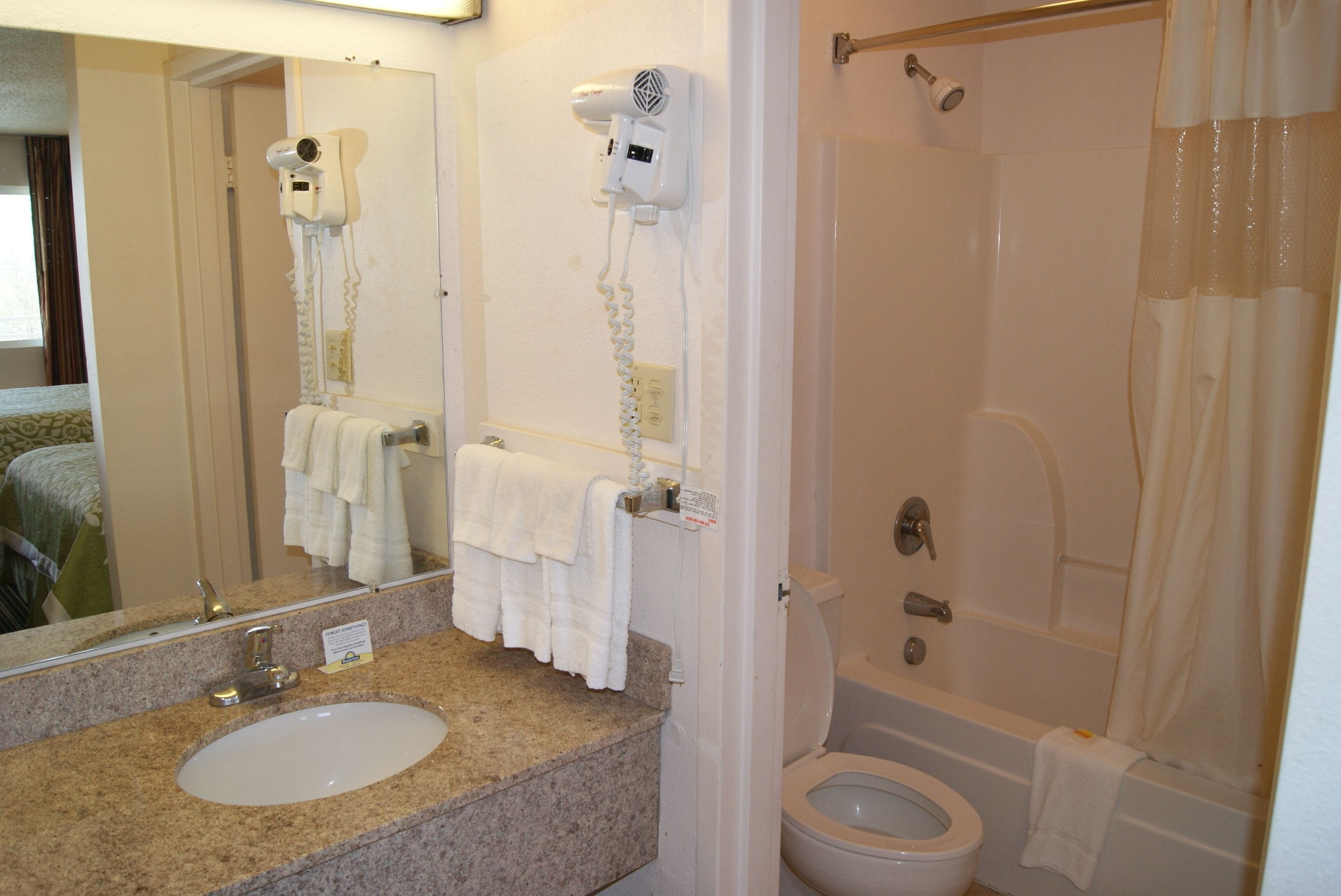 Un baño con lavamanos, espejo, toallero, secador de pelo y zona de ducha.