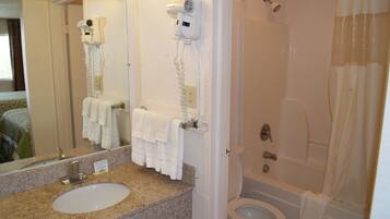 Un baño con lavamanos, espejo, toallero, secador de pelo y zona de ducha.