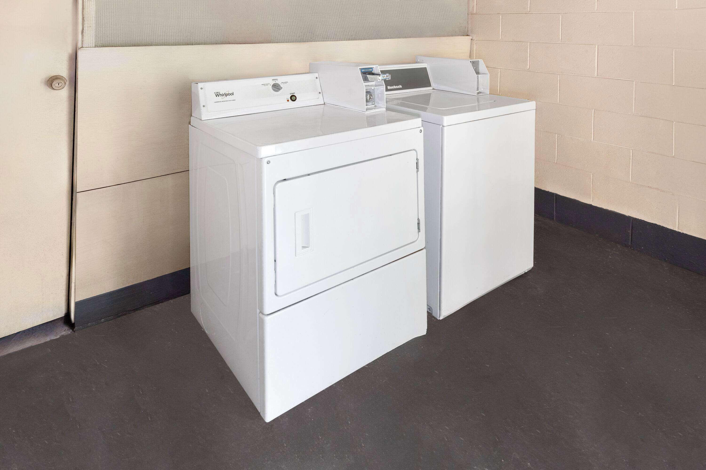 Une buanderie équipée de deux lave-linge et deux sèche-linge Whirlpool blancs.