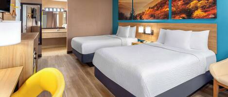 A hotel room with two beds, a desk, a chair, a bathroom, and a large painting on the wall.