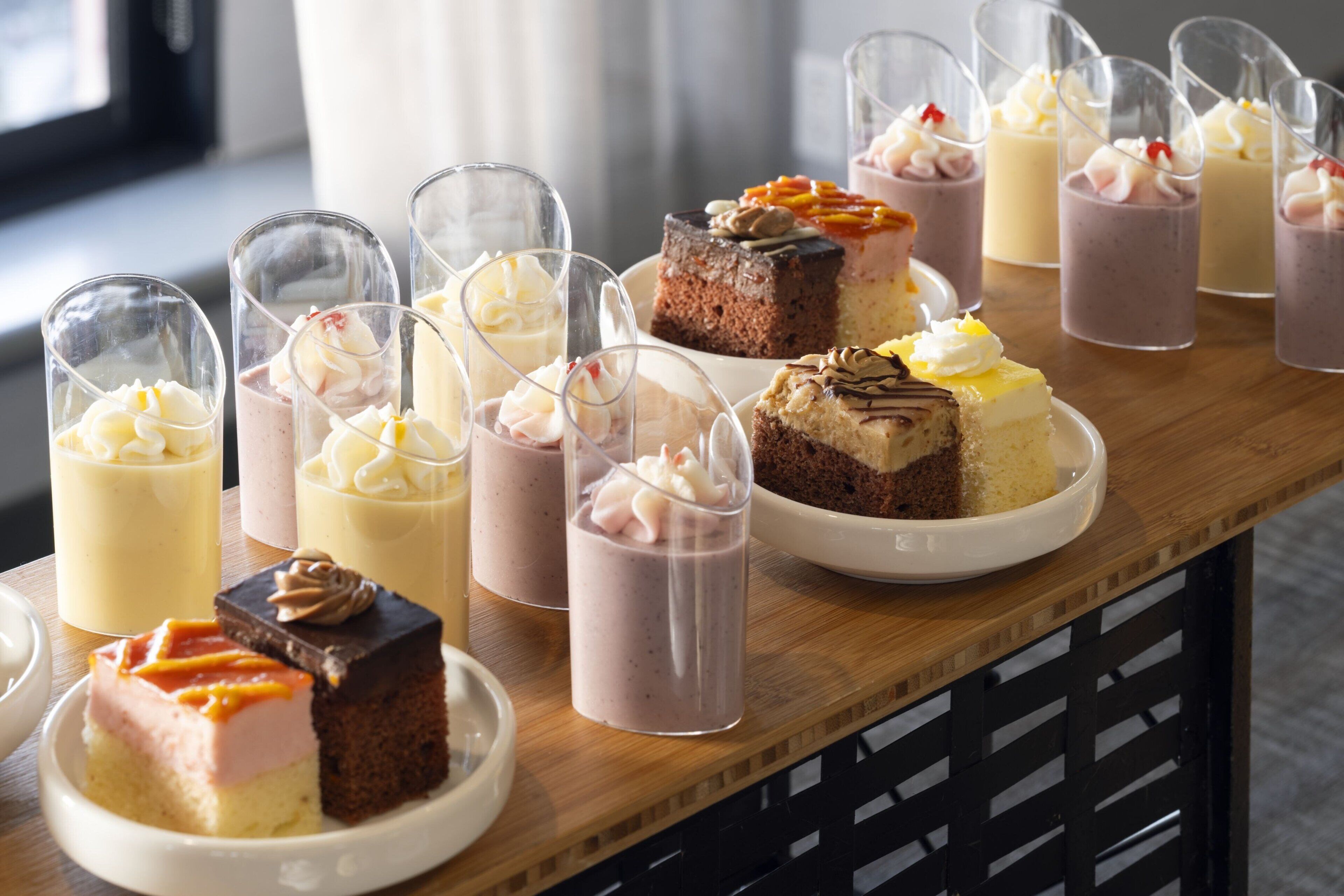 Verschiedene Desserts auf einem Holztisch, darunter Kuchen und Milchshakes in Gläsern.