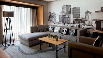 Uma sala de estar moderna com um sofá seccional, uma mesa de centro de madeira e um mural com vista para a cidade na parede.